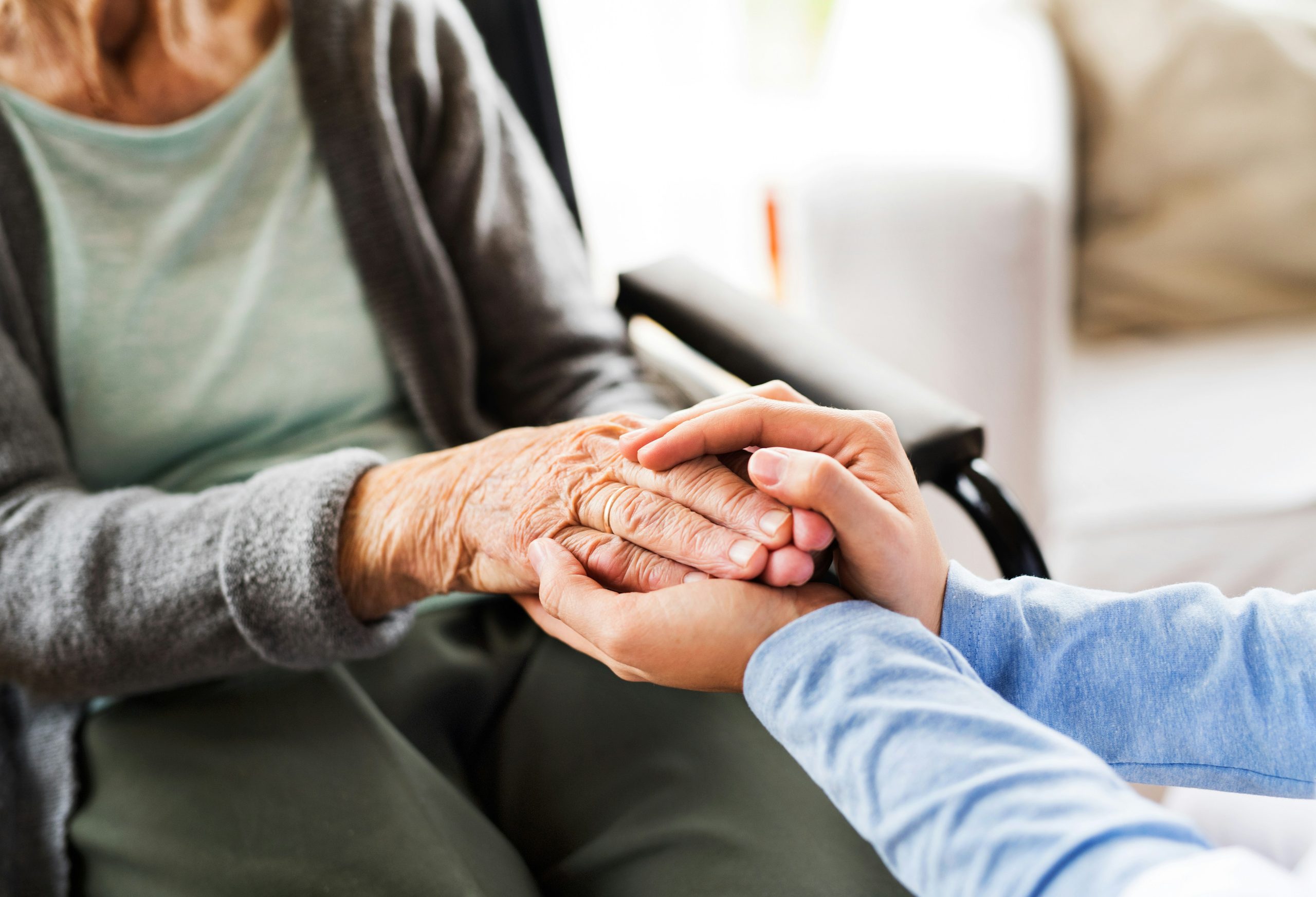 A caregiver gently holding the hand of an elderly resident